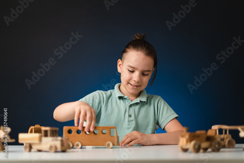 School boy playing, hands holding with wooden toys on white table, while staying at home on blue enlighted background photo