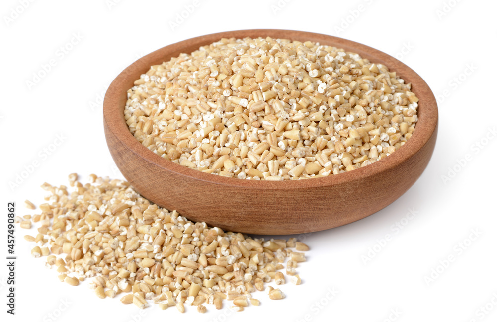 raw steel cut oats in the wooden plate, isolated on the white background raw steel cut oats in the wooden plate, isolated on the white background