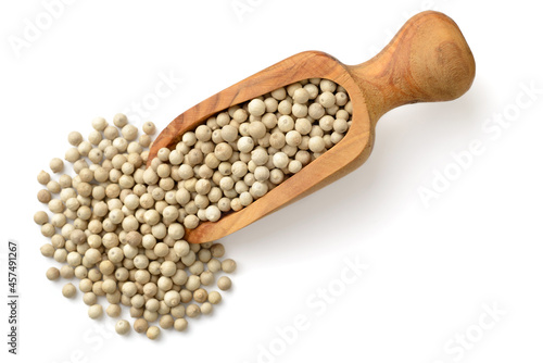 whole white peppercorns in the wooden scoop, isolated on the white background, top view