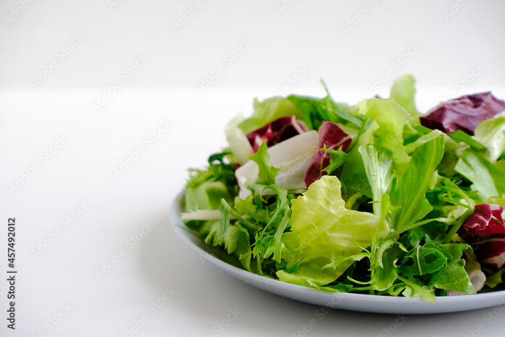 Bright fresh juicy raw salad greens. Escalora salad, frisee, radicchio, arugula salad in a gray plate on a white plate. Diet healthy food. Low-calorie, nutritious meal. Health care. Vitamin bowl. Bright fresh juicy raw salad greens. Escalora salad, frisee, radicchio, arugula salad in a gray plate on a white plate. Diet healthy food. Low-calorie, nutritious meal. Health care. Vitamin bowl.