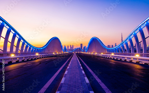 Beautiful view of Meydan Bridge in Dubai. Modern artistic bridge in Dubai. Night architectural shot of a bridge with curvy blue lights. photo