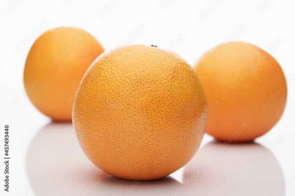 Three whole orange grapefruits isolated on white background, two of them are out of focus, bokeh Three whole orange grapefruits isolated on white background, two of them are out of focus, bokeh