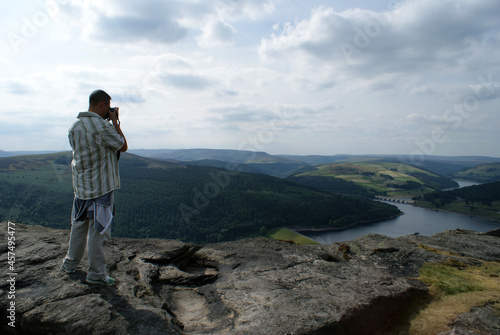 photographer taking photo on Bamford edge  looking out over the Ladybower Reservoir  Derwent Valley in Derbyshire  England