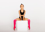 Little gymnast on a large white cube performs sports exercises