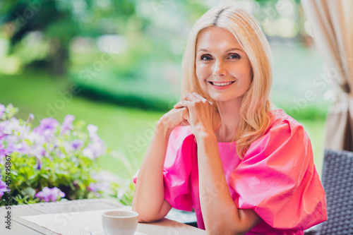 Photo portrait elder woman beautiful attractive with blonde hair sitting in cafe wearing pink dress © deagreez