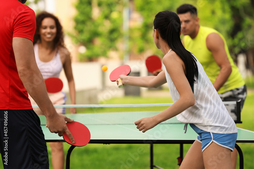 Friends playing ping pong outdoors on summer day photo