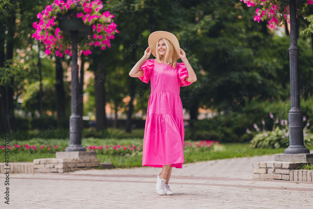 Full length body size photo woman wearing hat walking in green city park wearing long pink dress Full length body size photo woman wearing hat walking in green city park wearing long pink dress