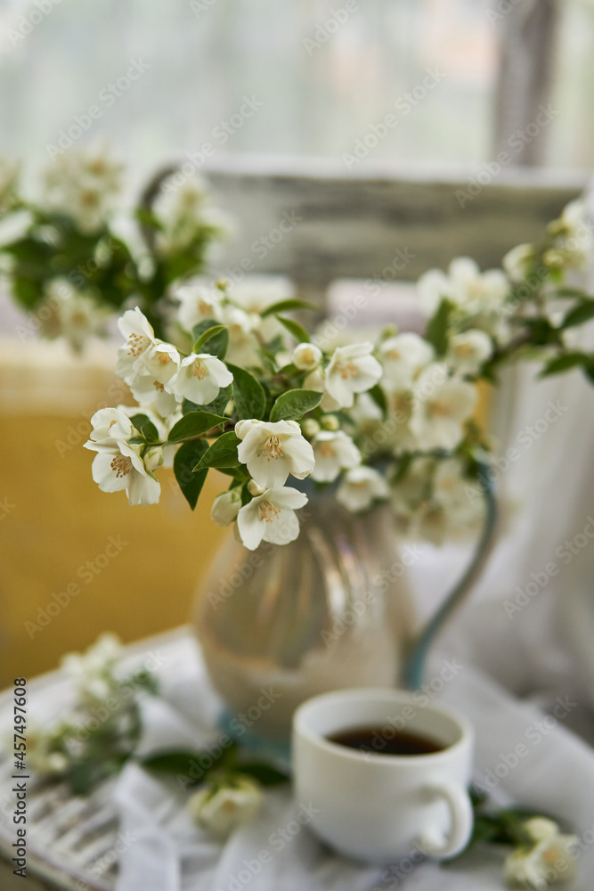Jasmine flowers in a white vase. Stillife with jasmine and cup of coffee. Jasmine flowers in a white vase. Stillife with jasmine and cup of coffee.