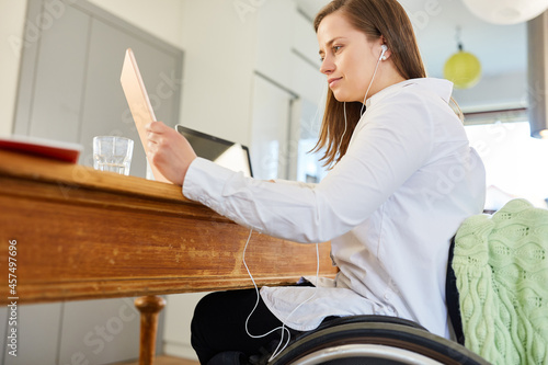 Frau im Rollstuhl am Tablet Computer im Home Office