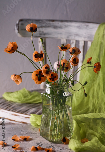 A Little Red Poppies Bouquet Arranged In Classical Style Stillife of popies in a glasses vase on vintage cher photo