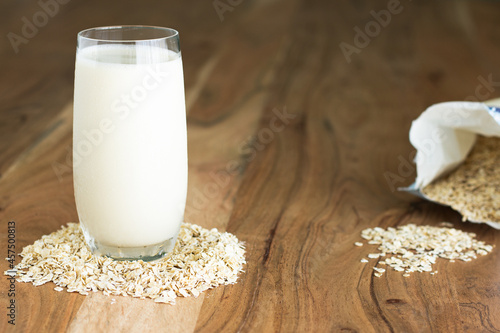 Glass of oat milk on oats and wood