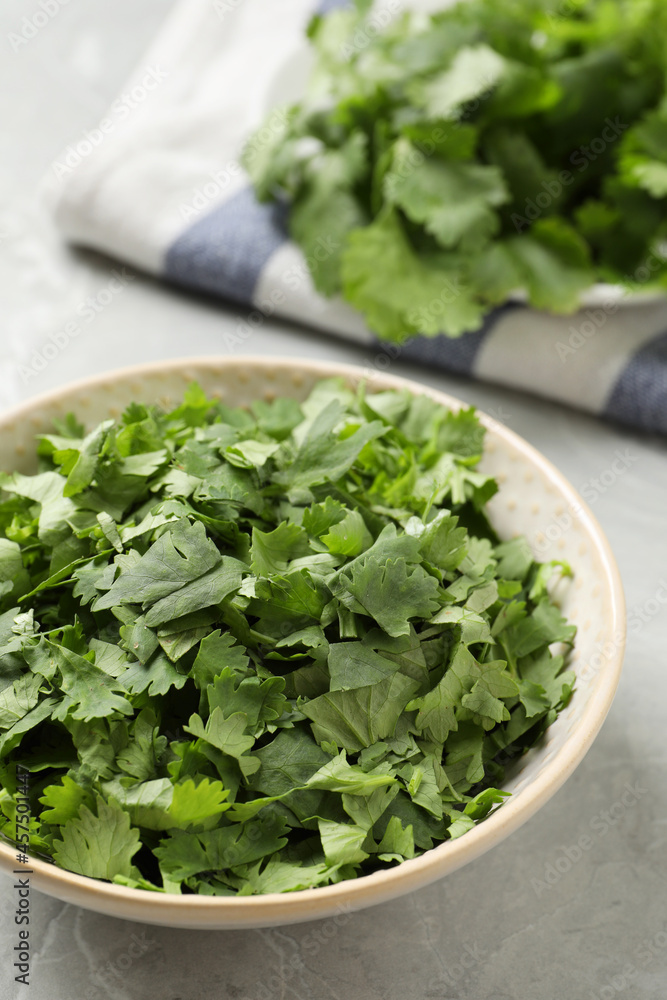 Cut fresh green cilantro in bowl on light grey marble table, closeup Cut fresh green cilantro in bowl on light grey marble table, closeup