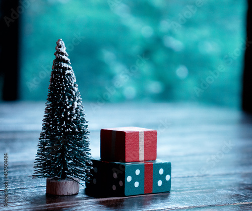 Merry Christmas and Happy new Year. Gift box and Christmas tree on the table near window