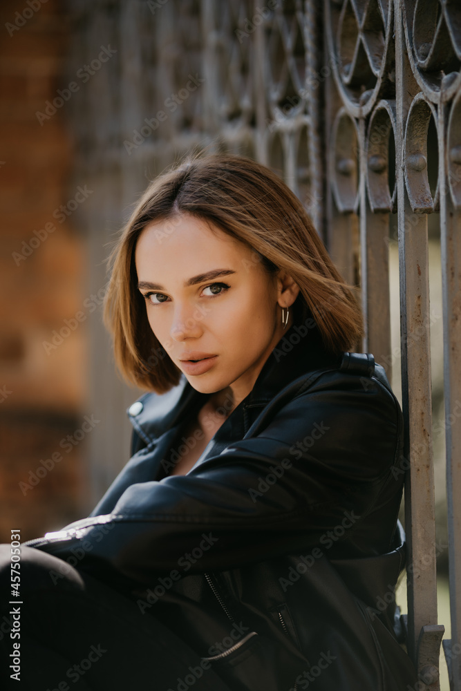 young stylish woman walking in street in fashionable outfit, wearing black leather jacket, spring autumn style, posing, high leather boots