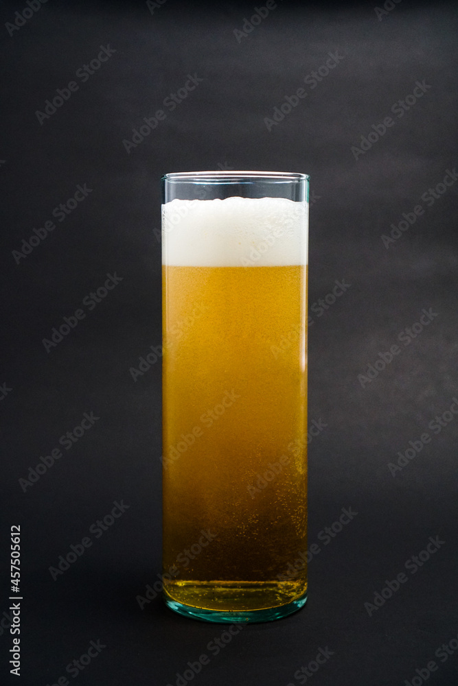 Pouring light beer from jar to glassware on black background with natural light set up. A glass of beer. Pouring light beer from jar to glassware on black background with natural light set up. A glass of beer.