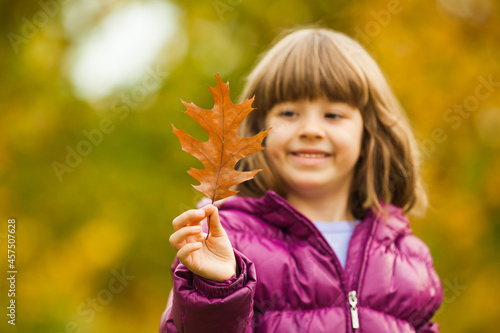 Happy little girl is enjoying autumn in park.