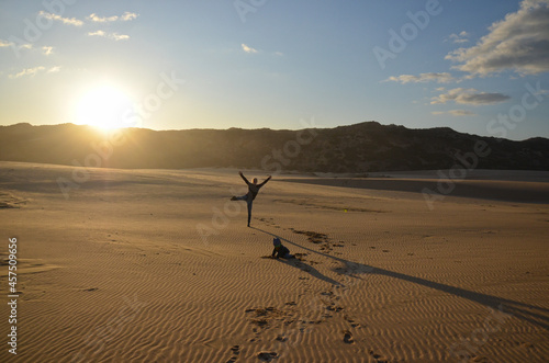 Woman standing on one leg on a beautiful beach at sunset in Portual, Algarve. photo