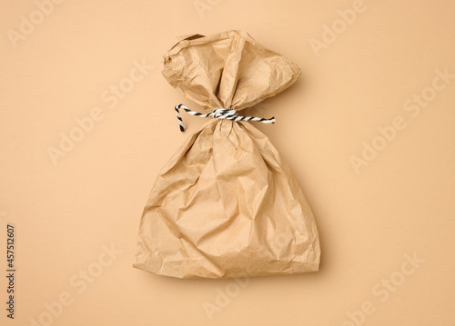full brown paper disposable food bag on a beige background, concept of delivery and ordering