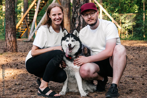 Portrait of happy couple with dog sitting on a training ground. A man and a woman with a husky smile happily at the camera. Dog training in the fresh air