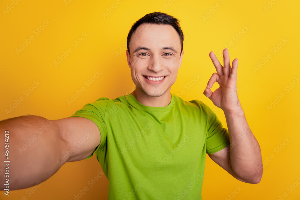Portrait of reliable funny guy make selfie show okey symbol on yellow background Portrait of reliable funny guy make selfie show okey symbol on yellow background