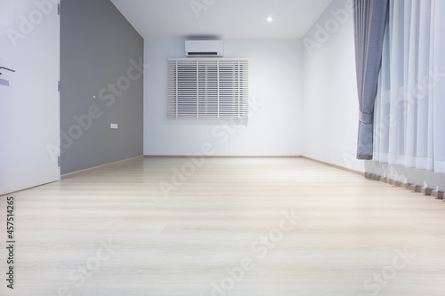 Empty room or bedroom at night. Interior inside house consist of wooden laminate floor, white gray wall, air conditioner, curtain and adjusting vertical blinds. New clean look modern for background.