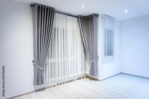 Empty room or bedroom at night. Interior inside house building consist of wooden laminate floor, white gray wall, window, curtain, adjusting blind and light. New clean look modern for background.