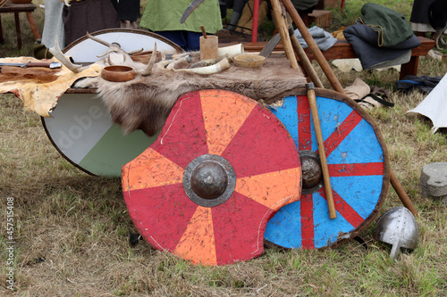 Battered Viking shields standing against a fur covered table. photo