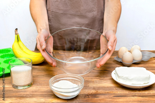 Caucasian woman chef in apron preparing ingredients for making cottage cheese banana muffins cupcakes casserole at home kitchen cuisine, online cooking, recipe instruction