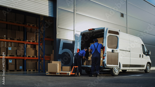 Photography Outside of Logistics Distributions Warehouse With Manager Using Tablet Computer, Workers Start Loading Delivery Truck with Cardboard Boxes