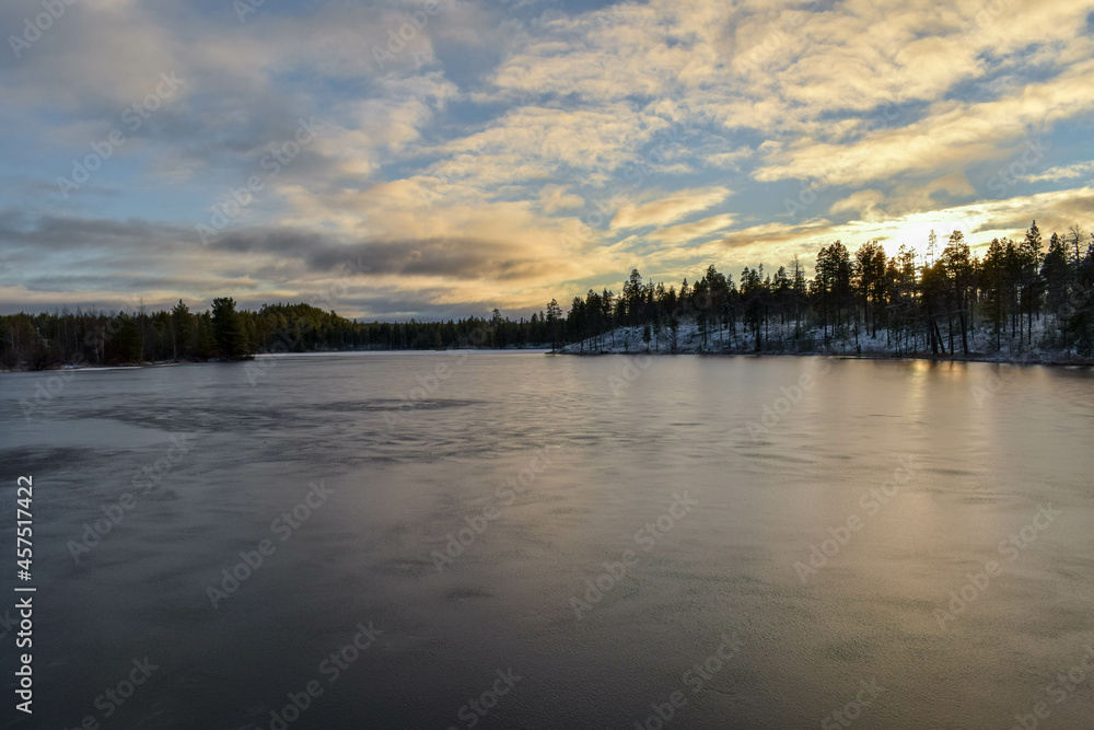 A small lake was covered with a thin layer of ice. Autumn evening in the north of Russia.