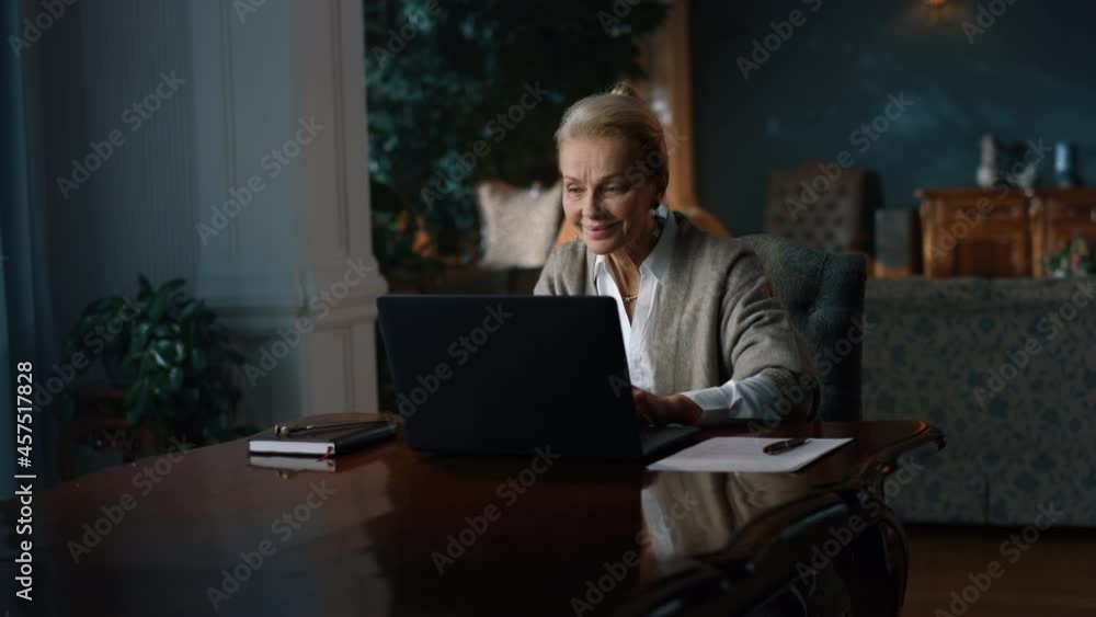 Smiling old woman reading good news on laptop computer at home Smiling old woman reading good news on laptop computer at home