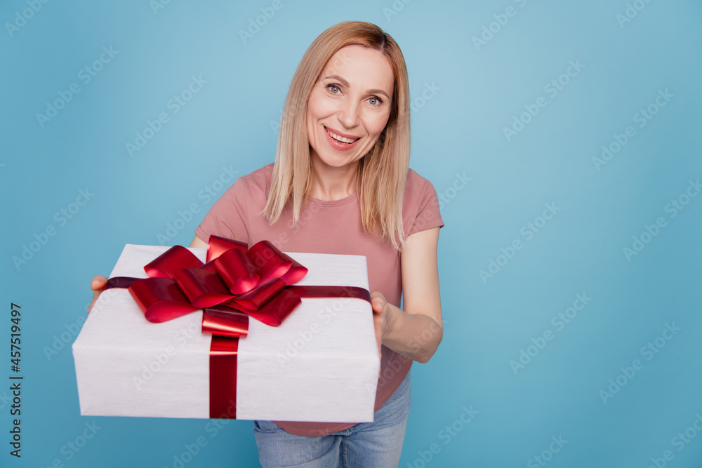 Photo of young attractive woman happy positive smile give present gift box guest party isolated over blue color background Photo of young attractive woman happy positive smile give present gift box guest party isolated over blue color background