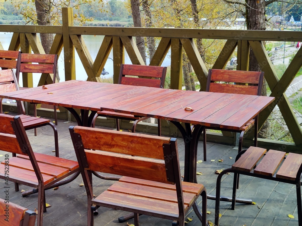 Autumn, tables in cafe on the roof with lake view, with yellow leaves on the floor 