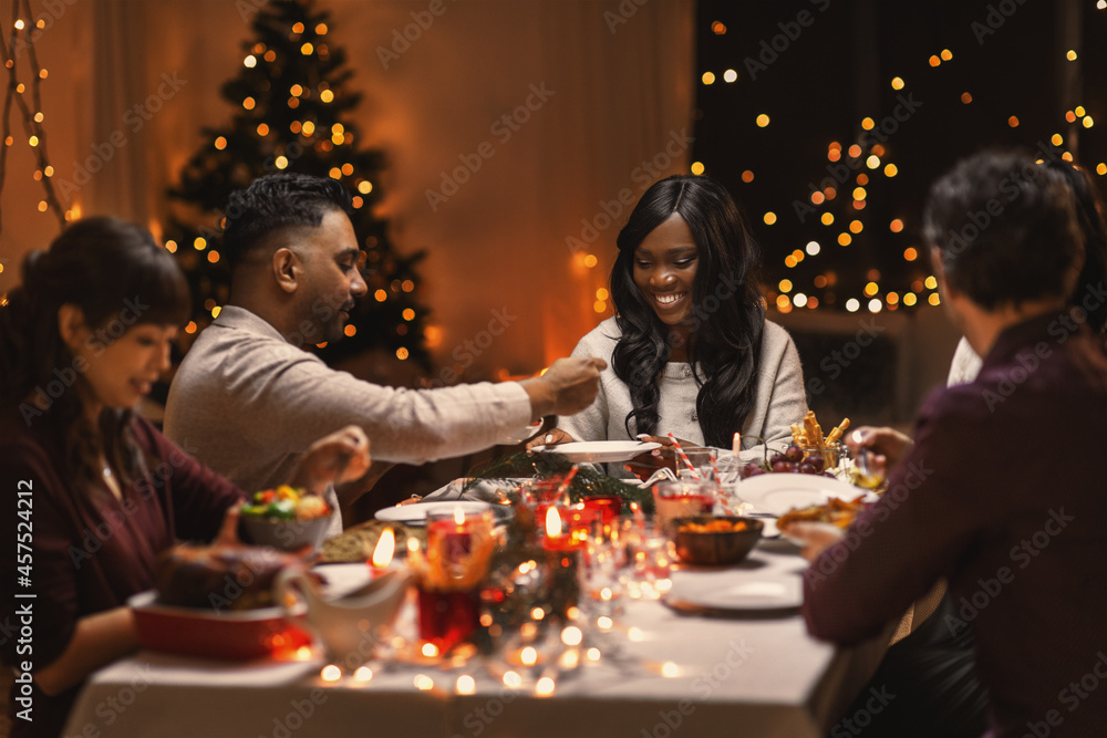 holidays, party and celebration concept - multiethnic group of happy friends having christmas dinner at home