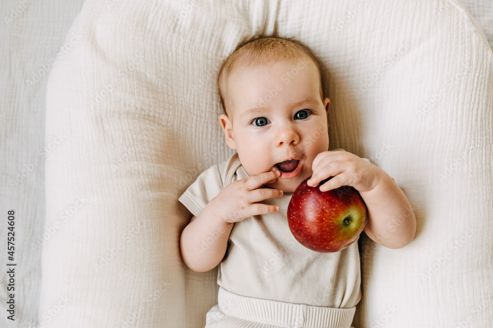 Baby holding a red apple. Food diversification concept. Baby holding a red apple. Food diversification concept.