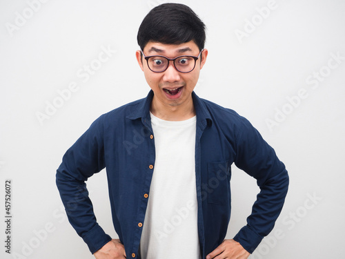 Asian man wearing glasses feeling amazed looking down on white background