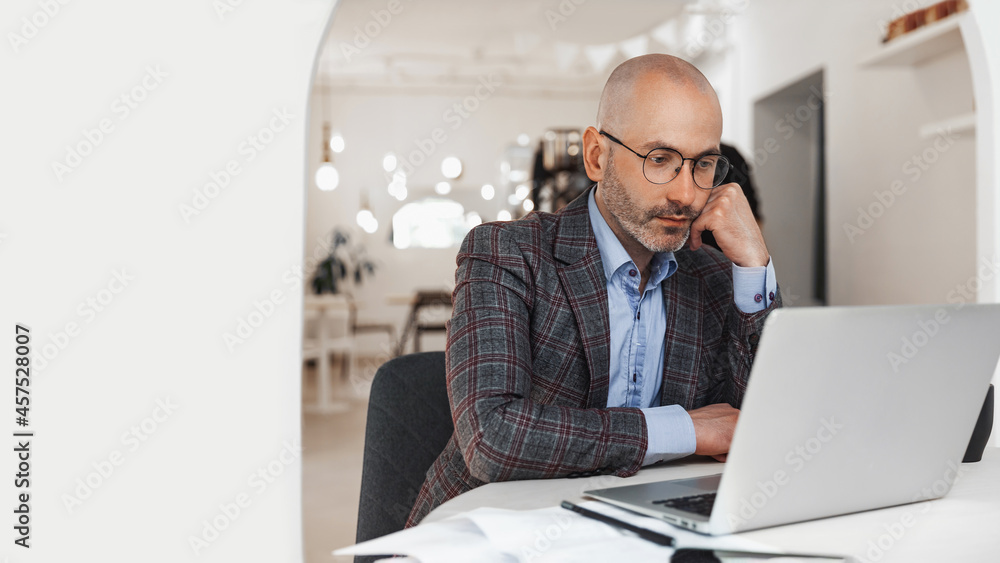 Businessman working on laptop in a cafe and ponders, free space for insertion Businessman working on laptop in a cafe and ponders, free space for insertion