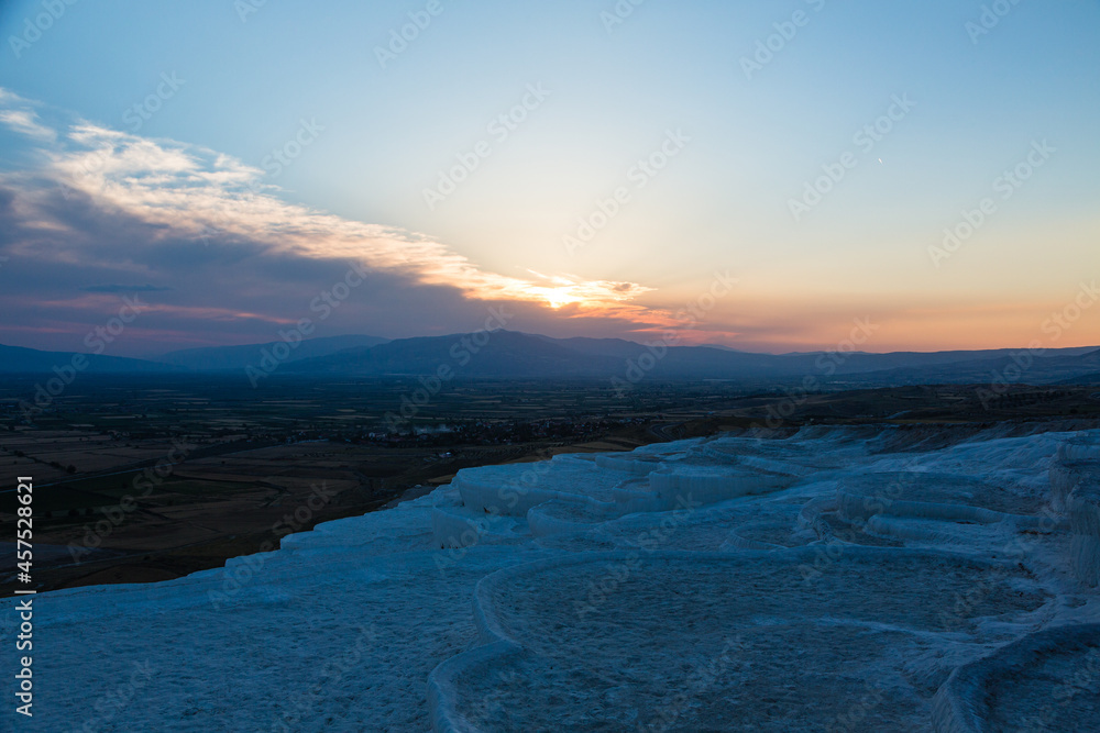 トルコ　ヒエラポリス・パムッカレの石灰棚と夕焼けでオレンジに染まった空と石灰華段丘から見える風景