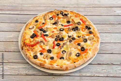 Vegan pizza with potato cheese with slices of black olives, slices of mushrooms, artichoke leaves and roasted peppers