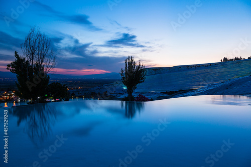 トルコ 夕暮れ時のヒエラポリス・パムッカレの石灰棚と青い水面