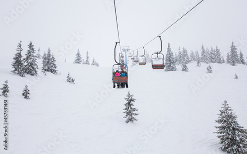 ski lift transports unrecognizable skiers over the snow-capped mountainside. cold winter cloudy day. winter active rest, sports hobbies, digital detox