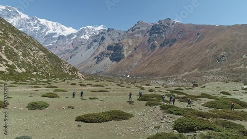 Trekking expedition moving over greenery landscape near snowy Chulu Peak mountain, Nepal photo