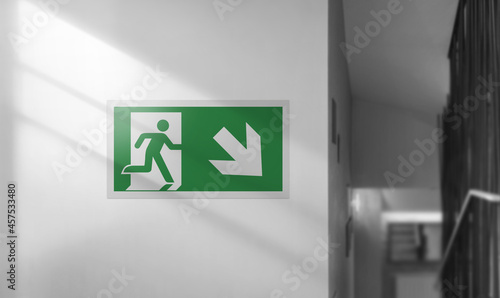 Foto Emergency exit sign on a white wall. Interior with stairs.