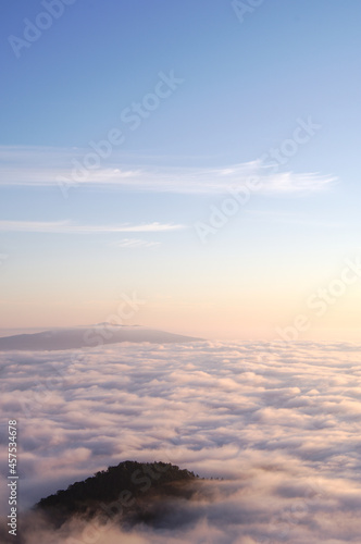 淡い色合いの青空の下に雲海の広がる風景。雲の間から見える山。ふんわりとした優しい雰囲気。 © Masa Tsuchiya
