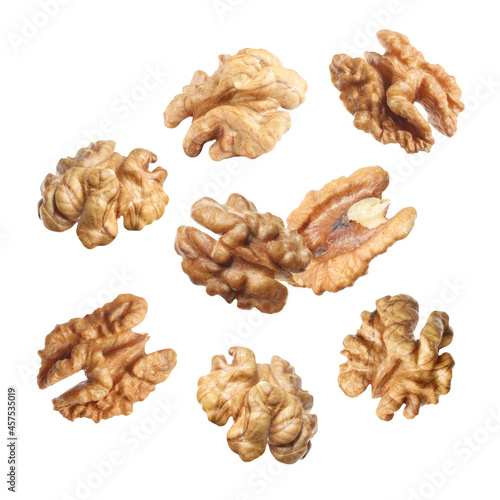 Halves of walnuts falling on white background