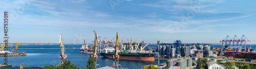 Port panorama, ship loading, harbor cranes and granaries in the cargo seaport