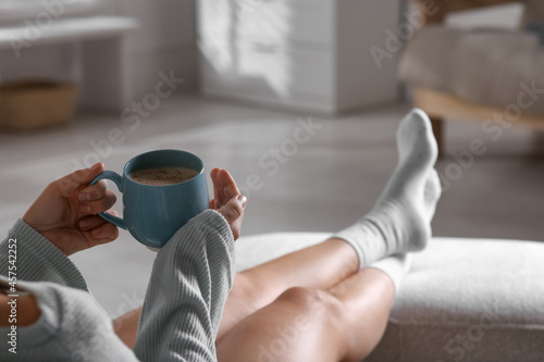 Woman with cup of aromatic coffee relaxing at home, closeup