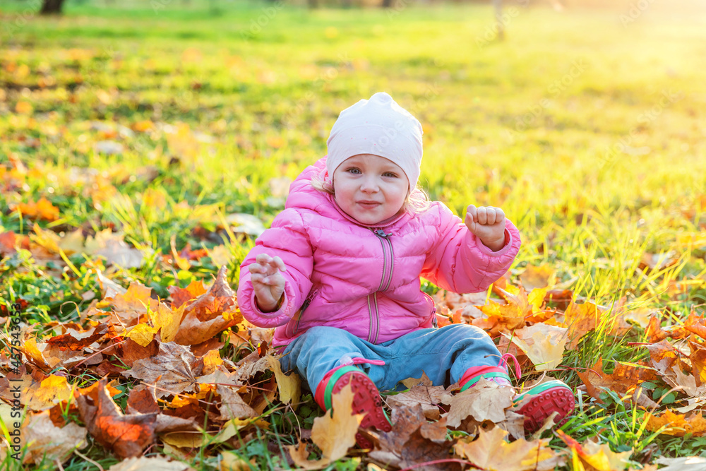 Happy young girl playing under falling yellow leaves in beautiful autumn park on nature walks outdoors. Little child throws up autumn orange maple leaves. Hello autumn concept. Happy young girl playing under falling yellow leaves in beautiful autumn park on nature walks outdoors. Little child throws up autumn orange maple leaves. Hello autumn concept.