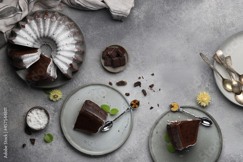 composition of pieces of homemade chocolate cake cupcake with pieces of chocolate on plates top view on a gray background horizontally