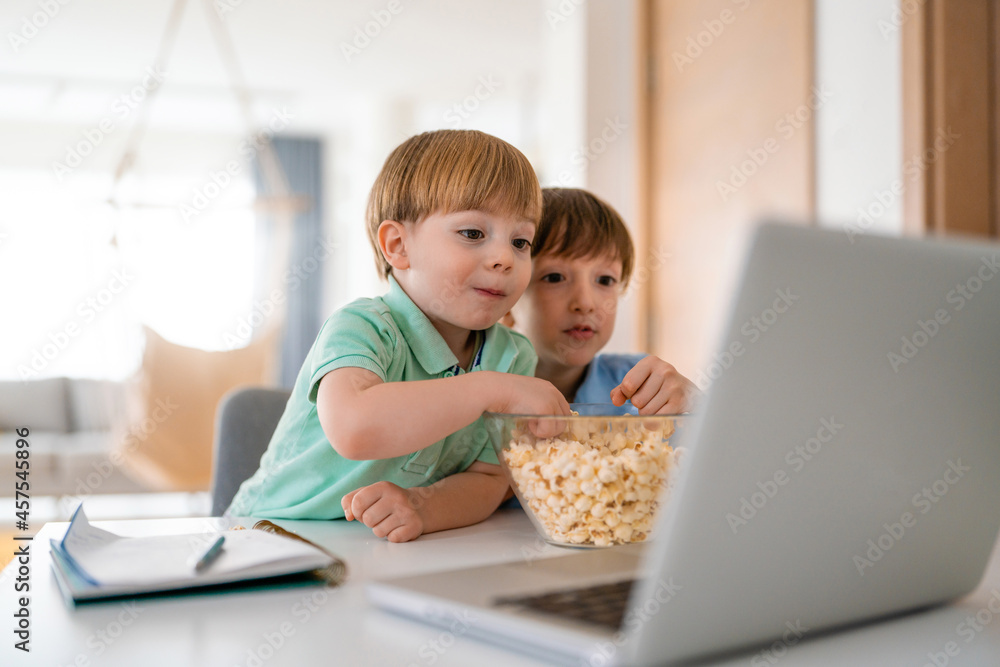 Cute children playing, watching movie on laptop at home. Digital addiction concept. Cute children playing, watching movie on laptop at home. Digital addiction concept.